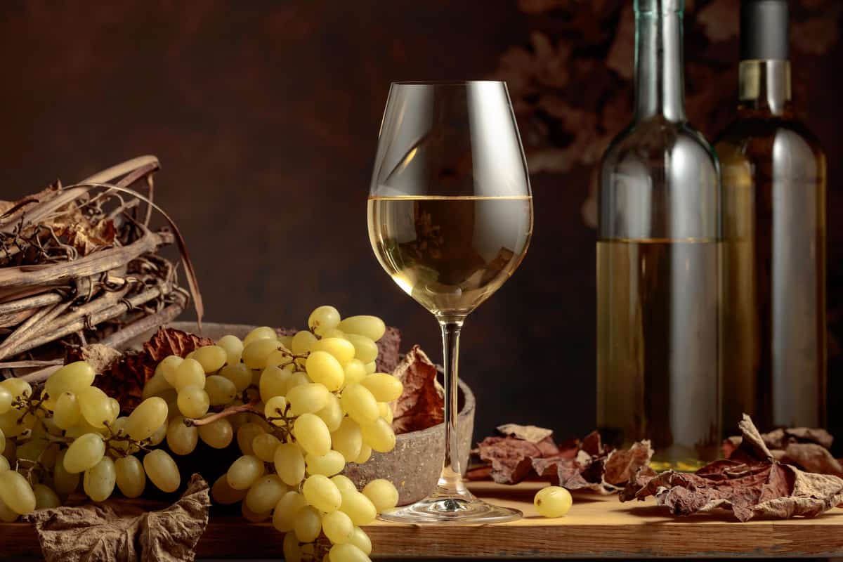 White wine and bunch of grapes on vintage wooden table.